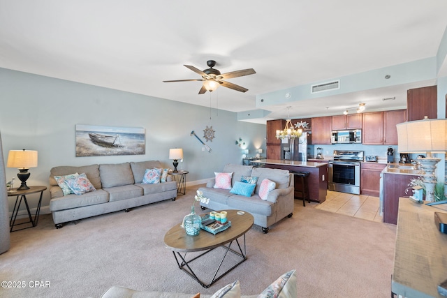 living room featuring ceiling fan with notable chandelier, light tile patterned floors, light carpet, baseboards, and visible vents