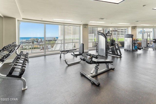 gym featuring expansive windows, visible vents, and a water view
