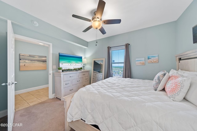 bedroom with baseboards, a ceiling fan, light carpet, and light tile patterned floors