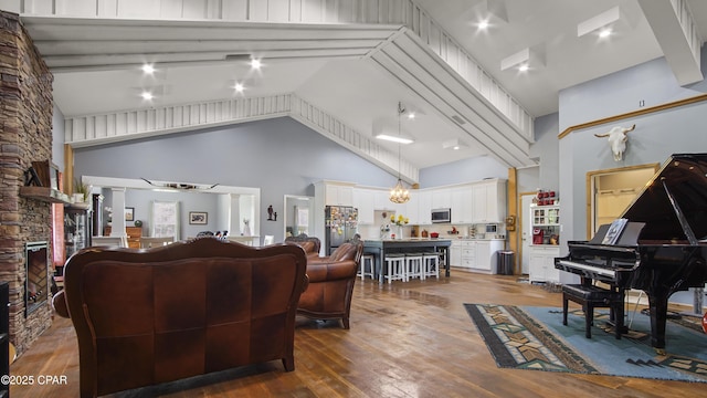 living room with high vaulted ceiling, dark wood-style floors, and a stone fireplace