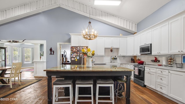 kitchen with dark wood-style flooring, white cabinetry, appliances with stainless steel finishes, and a kitchen breakfast bar