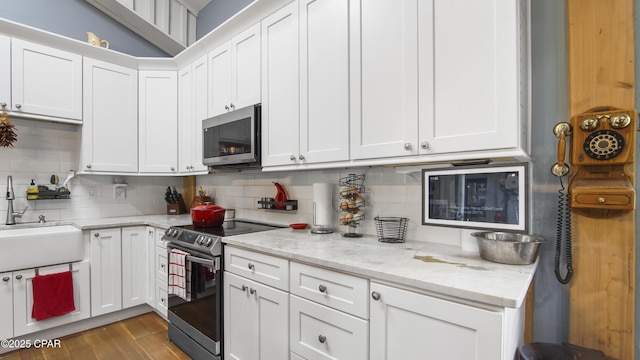 kitchen with a sink, appliances with stainless steel finishes, white cabinets, and tasteful backsplash