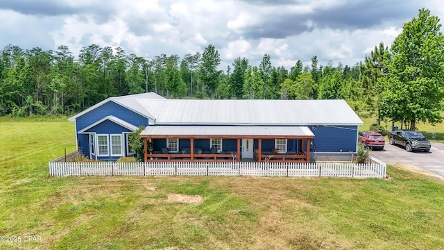 exterior space with covered porch, metal roof, fence private yard, and a front lawn