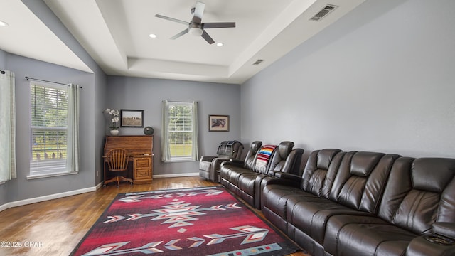 living area featuring ceiling fan, a tray ceiling, wood finished floors, and a wealth of natural light