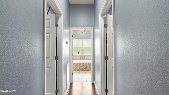 hall featuring baseboards, a textured wall, and dark wood-type flooring
