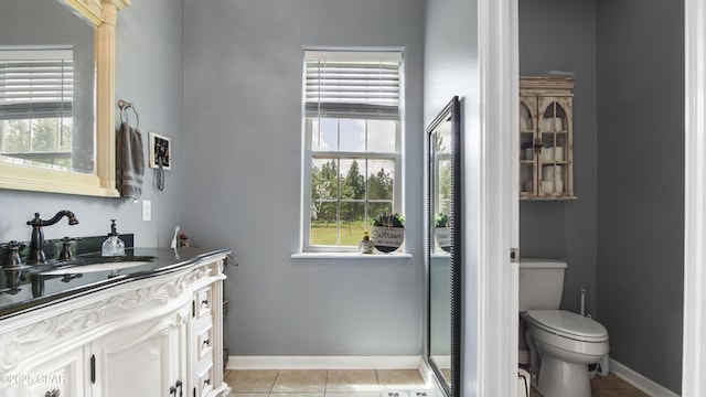 full bath featuring vanity, toilet, baseboards, tile patterned floors, and a wealth of natural light