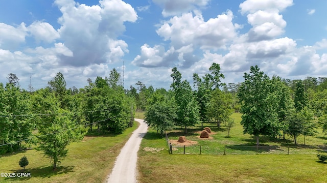 view of property's community featuring fence, a yard, and a rural view