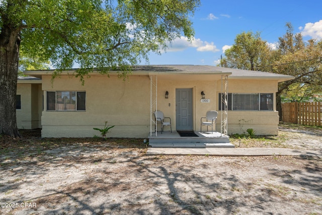 view of front facade featuring stucco siding and fence