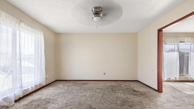unfurnished room featuring carpet flooring, baseboards, and a ceiling fan