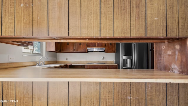 kitchen featuring under cabinet range hood, a peninsula, fridge with ice dispenser, and stainless steel gas cooktop