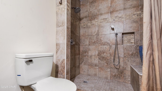 bathroom with a tile shower and toilet