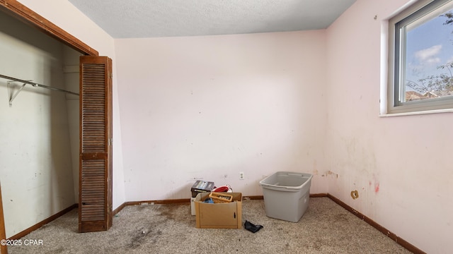 unfurnished bedroom featuring a textured ceiling, a closet, carpet flooring, and baseboards