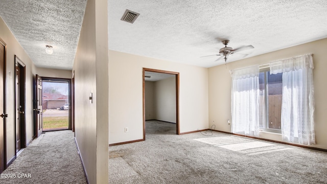 carpeted empty room featuring a textured ceiling, visible vents, baseboards, and ceiling fan