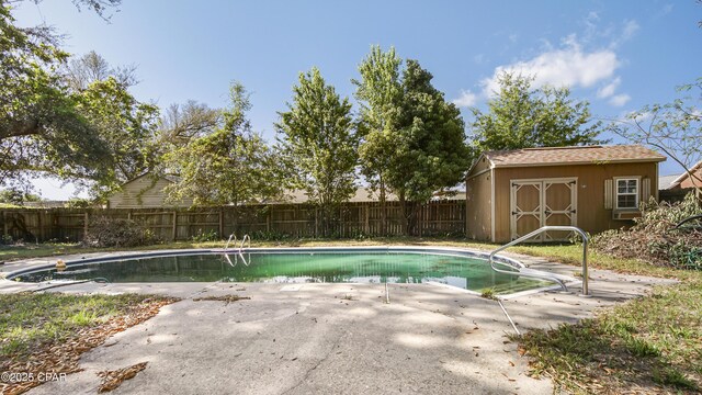 view of swimming pool featuring a storage shed, a fenced backyard, an outbuilding, a fenced in pool, and a patio