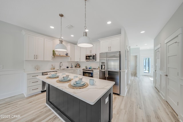 309 Paridiso Pl Unit A, Panama City Beach, FL 32413 - kitchen featuring stainless steel appliances, a sink, white cabinetry, light wood finished floors, and a center island