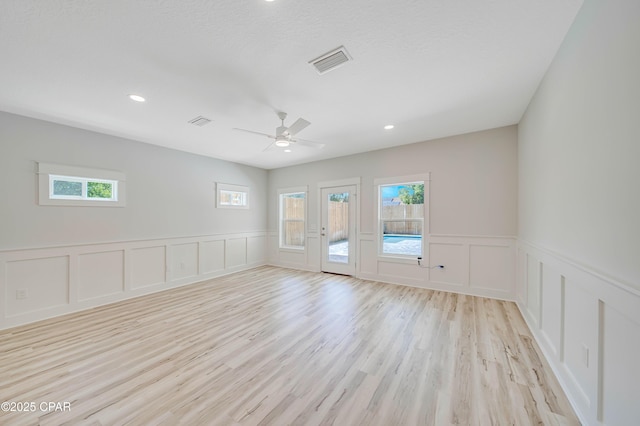 309 Paridiso Pl Unit A, Panama City Beach, FL 32413 - spare room with a decorative wall, plenty of natural light, light wood-type flooring, wainscoting, and ceiling fan