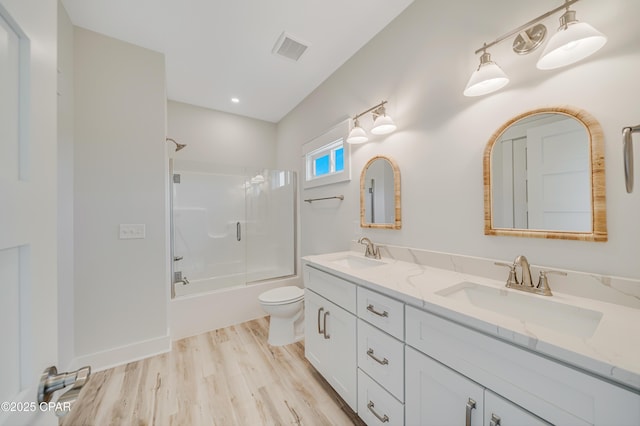 309 Paridiso Pl Unit A, Panama City Beach, FL 32413 - bathroom with toilet, bath / shower combo with glass door, double vanity, and wood finished floors