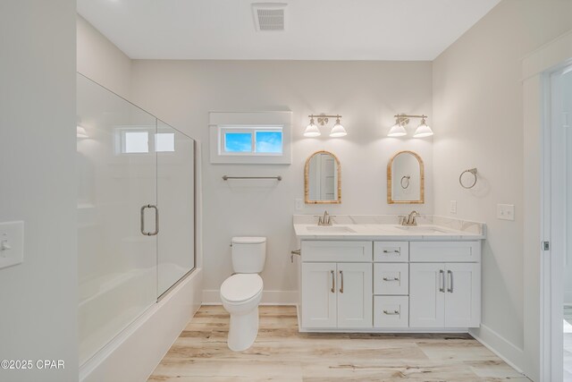 309 Paridiso Pl Unit A, Panama City Beach, FL 32413 - bathroom featuring double vanity, toilet, wood finished floors, shower / bath combination with glass door, and baseboards