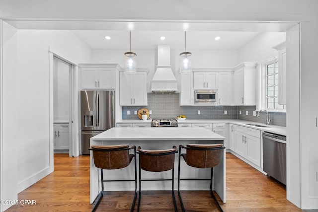 1502 Match Point Ln Unit 402, Panama City Beach, FL 32413 - kitchen featuring stainless steel appliances, custom exhaust hood, a kitchen island, a breakfast bar area, and white cabinetry