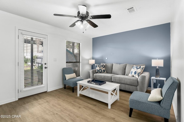 living area featuring visible vents, light wood-type flooring, baseboards, and ceiling fan