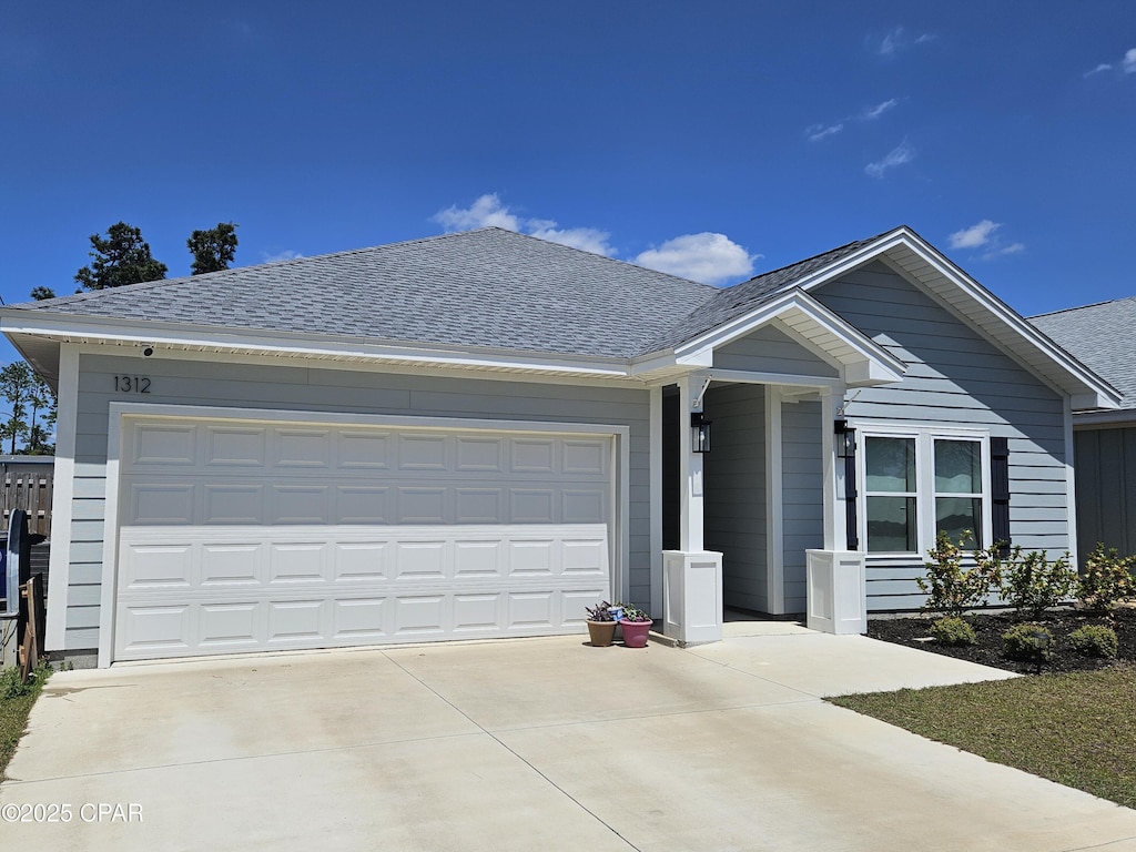 single story home with concrete driveway, a shingled roof, and a garage
