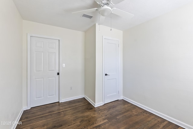unfurnished bedroom with baseboards, a ceiling fan, visible vents, and dark wood-style floors