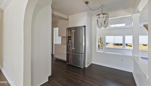 kitchen featuring a textured ceiling, a chandelier, high quality fridge, white cabinets, and dark wood-style flooring