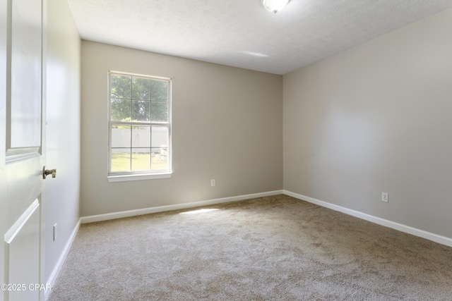 spare room featuring carpet floors, a textured ceiling, and baseboards