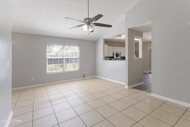 unfurnished living room featuring light tile patterned flooring, a textured ceiling, a ceiling fan, baseboards, and lofted ceiling