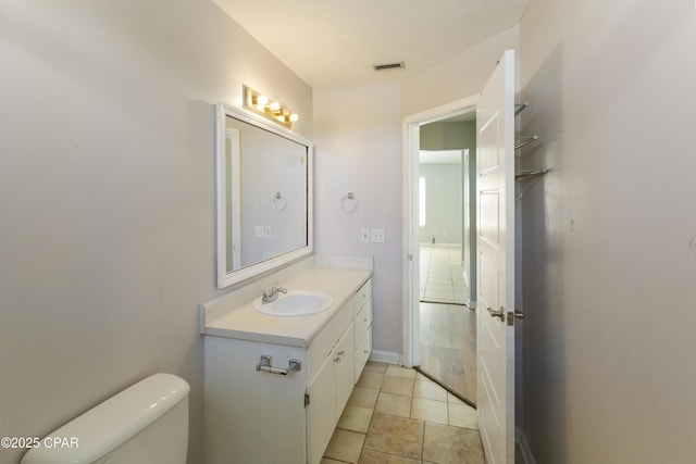 half bath with vanity, tile patterned flooring, toilet, and visible vents