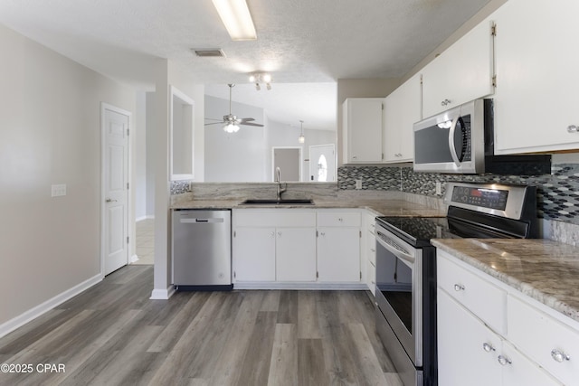 kitchen with a sink, stainless steel appliances, a ceiling fan, decorative backsplash, and visible vents