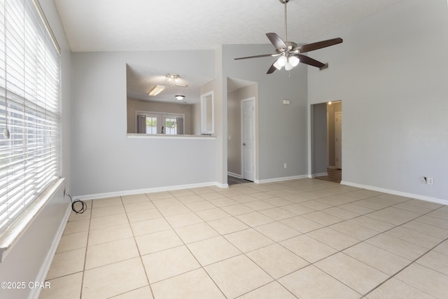 spare room with a ceiling fan, baseboards, light tile patterned flooring, and lofted ceiling