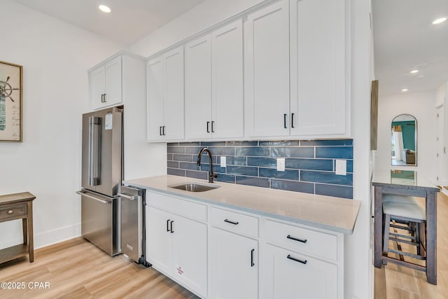 13643 Front Beach Rd, Panama City Beach, FL 32413 - kitchen with stainless steel appliances, light wood-type flooring, decorative backsplash, light stone counters, and white cabinets