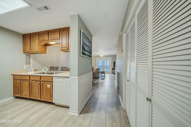 kitchen featuring visible vents, white dishwasher, light countertops, a sink, and light wood finished floors