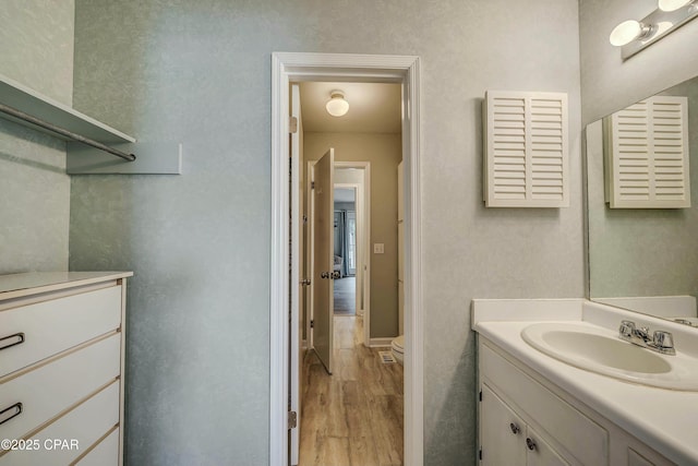 bathroom featuring vanity, wood finished floors, and toilet