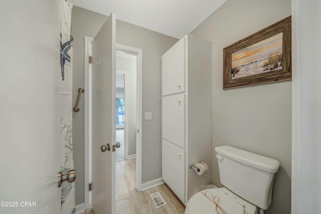 bathroom featuring visible vents, baseboards, wood finished floors, and toilet