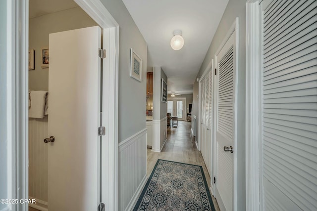 hallway featuring a wainscoted wall and light wood-type flooring