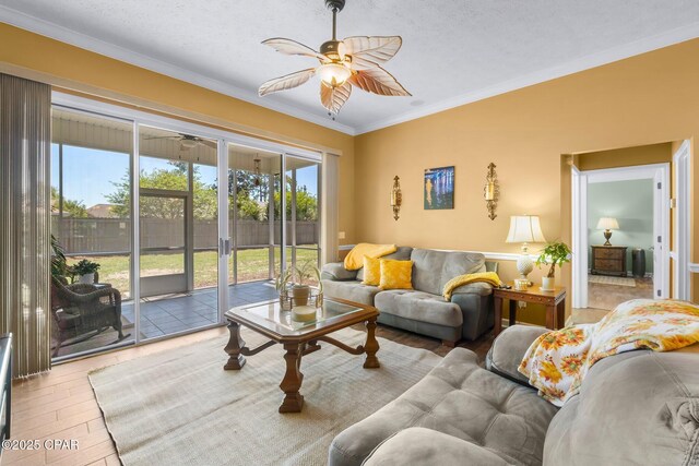 living area with crown molding, ceiling fan, and wood finished floors