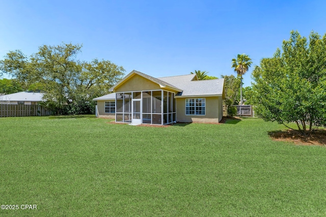 rear view of property featuring a sunroom, a yard, stucco siding, and fence