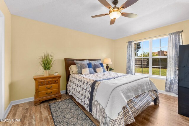 bedroom with baseboards, ceiling fan, and wood finished floors