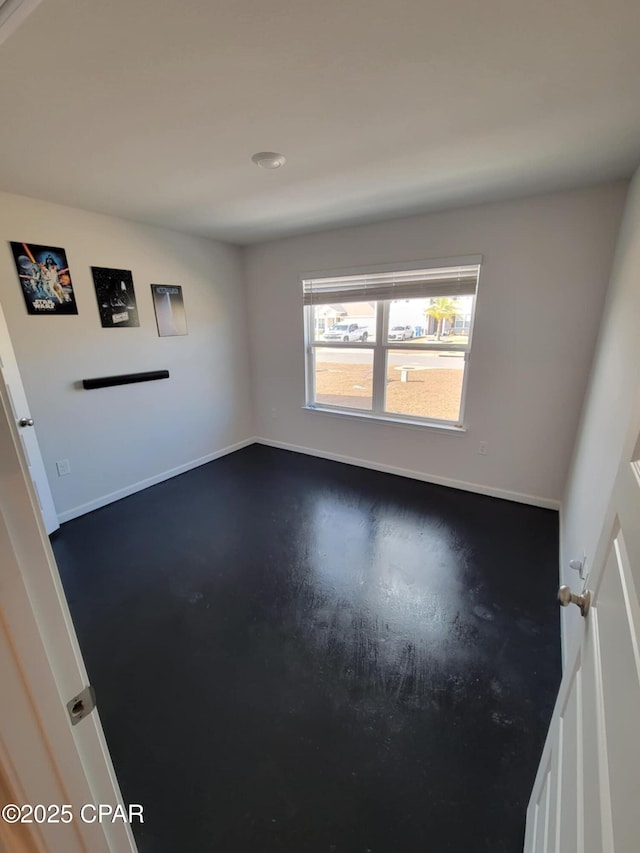 empty room with baseboards and concrete floors