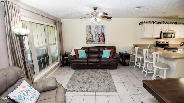 living room with ceiling fan, light tile patterned flooring, a textured ceiling, and visible vents