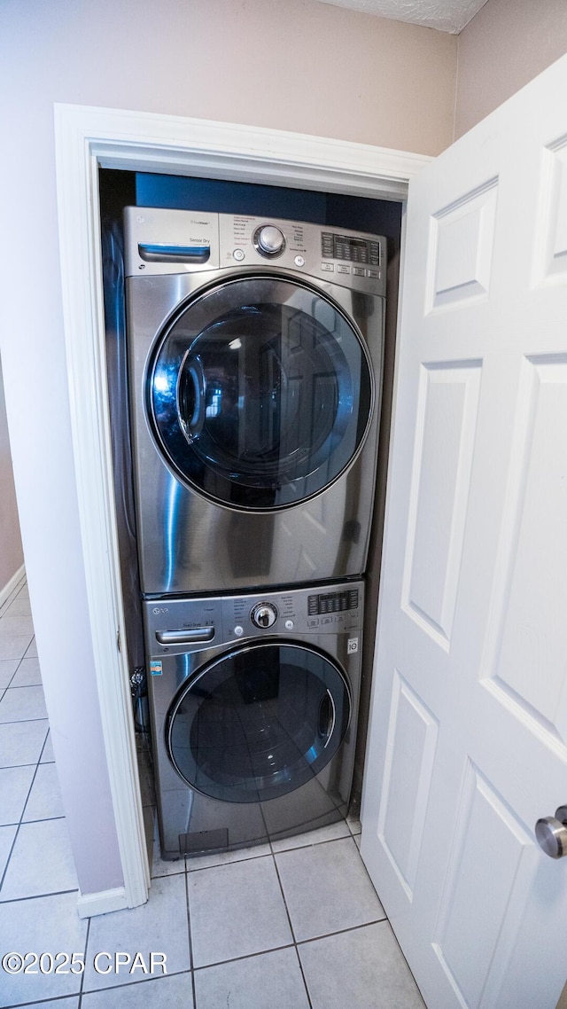washroom featuring stacked washer / drying machine, laundry area, and light tile patterned floors