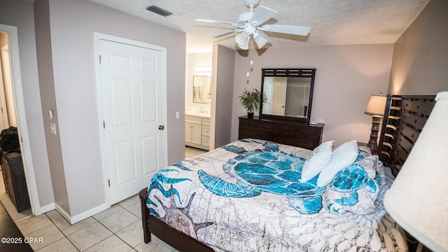 bedroom with a textured ceiling, visible vents, ceiling fan, connected bathroom, and light tile patterned floors
