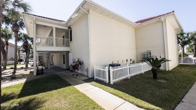 view of home's exterior featuring stucco siding, a yard, stairway, and fence