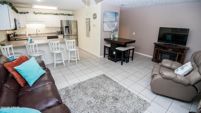 living area featuring a textured ceiling, baseboards, and light tile patterned floors