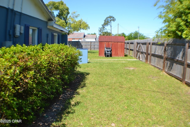 view of yard featuring a storage unit, an outbuilding, and a fenced backyard