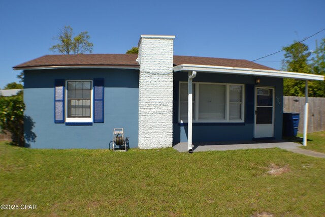 view of front of property featuring fence, a chimney, a front yard, and stucco siding