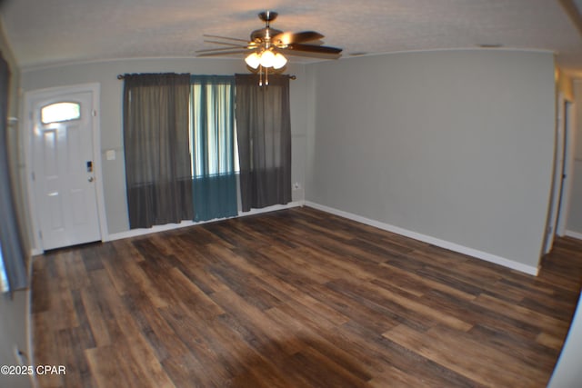 interior space with a ceiling fan, baseboards, and dark wood-style flooring