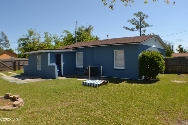 rear view of house with a patio area, a fenced backyard, a yard, and central AC unit